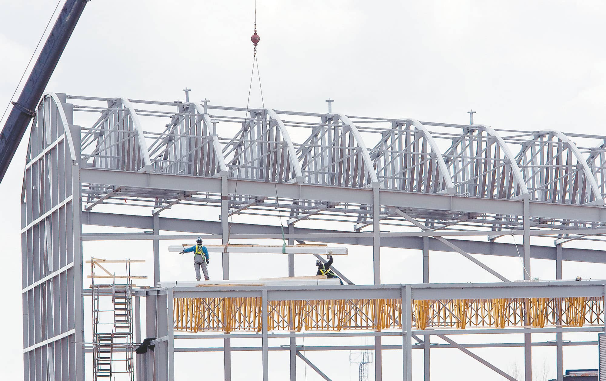 Background image of workers working on rooftop structural steel trusses